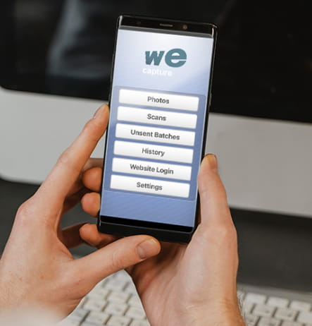 Photo of hands holding a phone with the We-Capture app on the screen